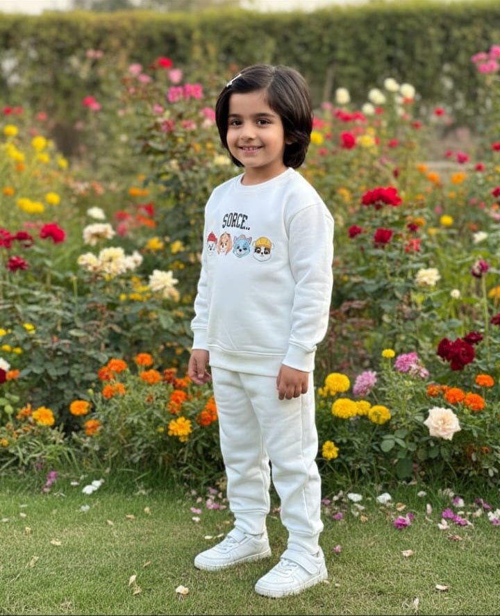 Boy wearing a cream MODST sweatshirt and joggers set in a flower garden